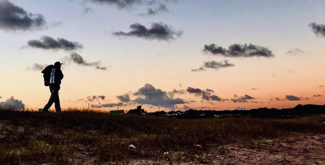 Plácido Salles andando em praia com horizonte ao fundo