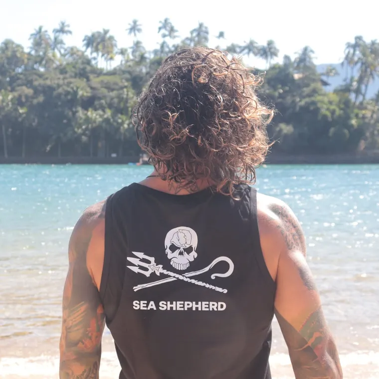 Apoiador de costas, na praia, vestindo uma regata da Sea Shepherd