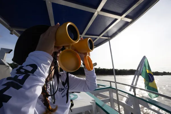 Voluntária observa o rio com binóculos a bordo de um barco da Sea Shepherd Brasil na Amazônia