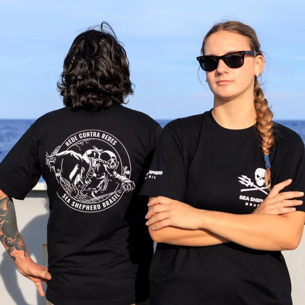 Dois tripulantes no convés vestindo a camiseta Rede Contra Redes, um de costas e outra de frente