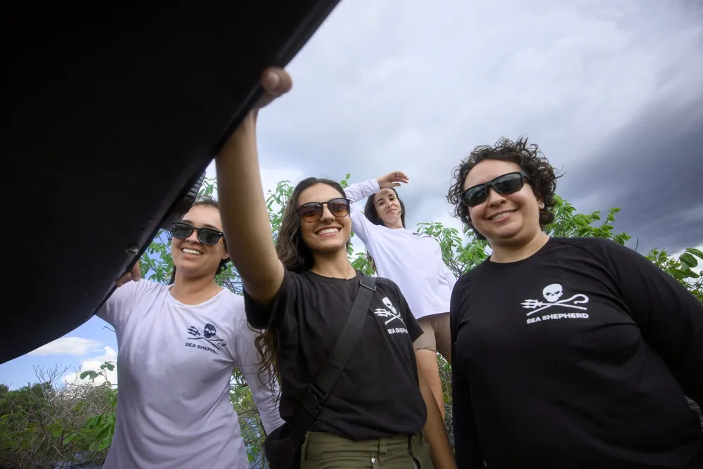 Quatro voluntárias da Sea Shepherd Brasil sorriem ao ar livre, vestindo camisetas da organização