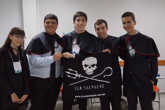 Professores conselheiros e alunos juízes posam com a bandeira da Sea Shepherd