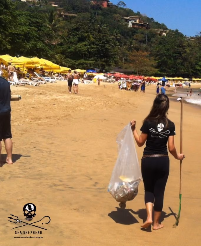 Equipe Sea Shepherd Brasil na areia da praia recolhendo embalagem de alimentos e bitucas de cigarro.
