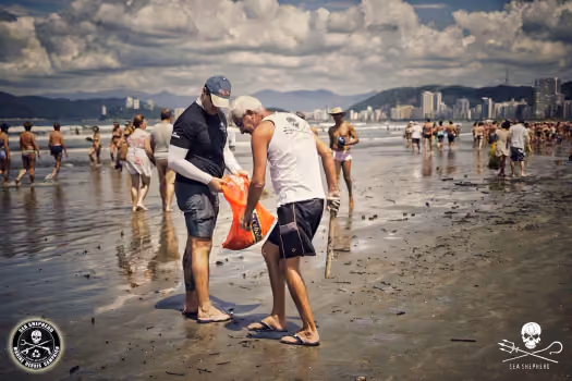 Voluntários em dupla coletando o micro lixo na beira d´água.