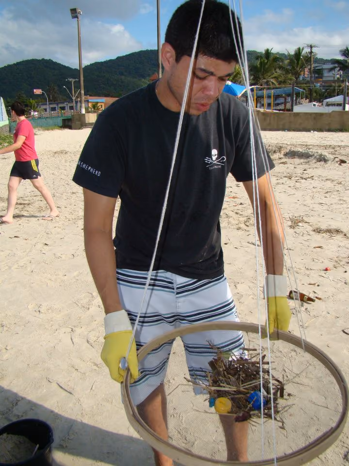 Peneirando a areia em busca de bitucas e plástico.