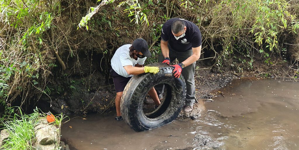 Voluntários retirando pneu do rio