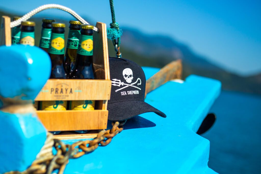Garrafas de cerveja Praya junto a um boné do Sea Shepherd
