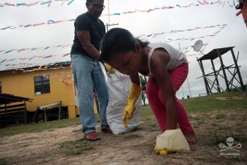 Criança limpando resíduos em ação com um adulto observando
